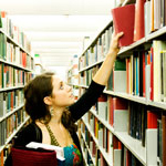 Student Reaching for Book from Shelf