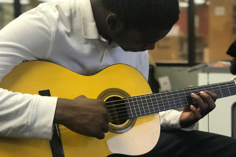 Tight shot of teen playing classical guitar