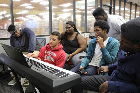 Mentor teaching teens to play music keyboard