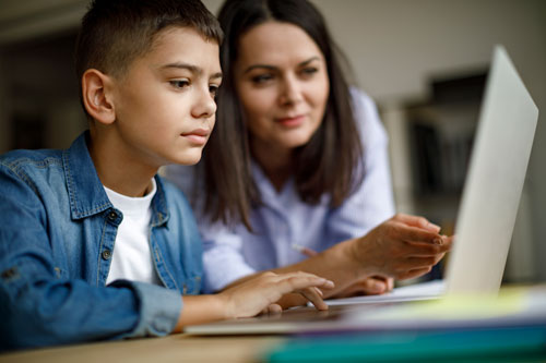 Mother helping son with homework on laptop
